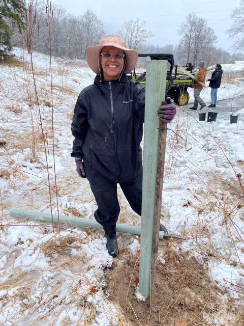 Volunteer poses with newly planted tree