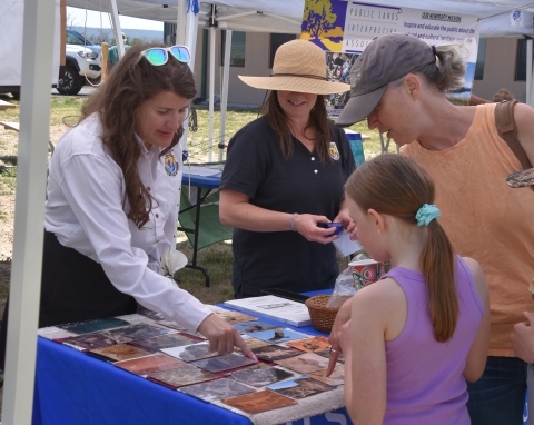 Two adults in FWS uniform show photographs to visitors.