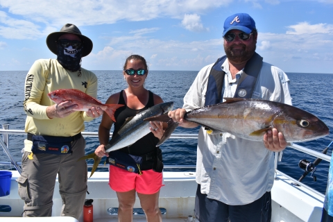Anglers stand on fishing vessel holding three different sportfish species 
