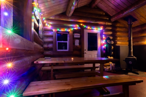 Colored lights decorate the cozy interior of the Dolly Varden log public use cabin at Kenai Refuge on Dolly Varden Lake.