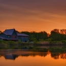 Green visitor center building with orange sunrise reflected in the pond in front. 