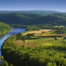 a river winds through lush farm land and rolling hills