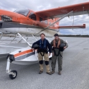 two people stand in front of an airplane