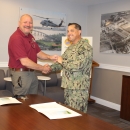two men shake hands while standing behind large table