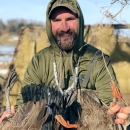person wears a necklace of bands and holds ducks in hands