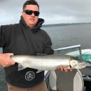 Fish biologist, Ryan Koch, holding a fish while standing on a boat