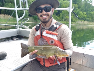 Image of biologist holding a fish in a boat.
