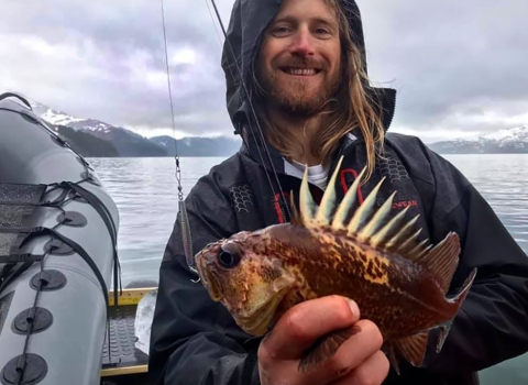 a man with long hair holding a spiky fish
