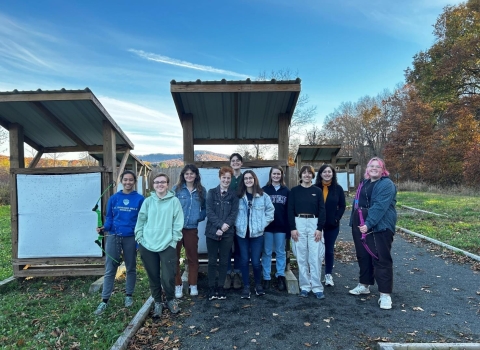 Ten students from Mt. Holyoke stand in front of targets at the Fort River Archery Range.