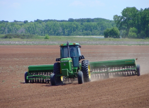 Tractor planting seed in plowed field