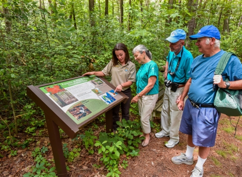 FWS Visitor services staffer shows interpretive panel to visitors