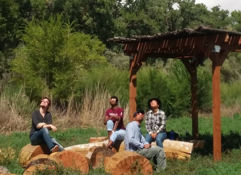 Group sits at Valle de Oro's outdoor classroom to watch the solar eclipse