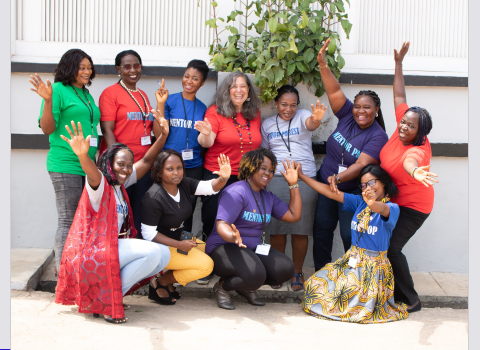 A group of women smiles and waves towards the camera