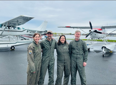 four people standing in front of airplans
