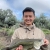 Ywj Pheej Yang holding a largemouth base with a natural setting in the background