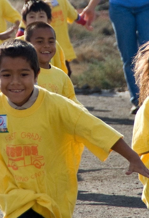 Kids in yellow shirts run at Don Edwards San Francisco Bay National Wildlife Refuge, while on an elementary school field trip.