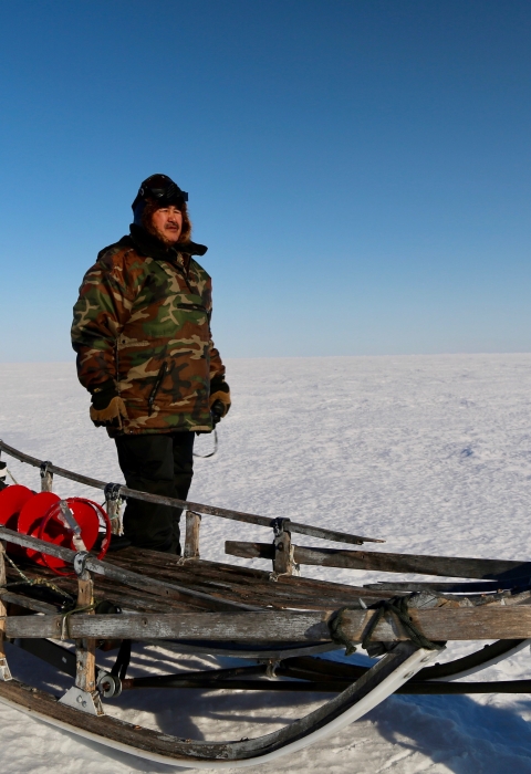 man standing by a sled on snow