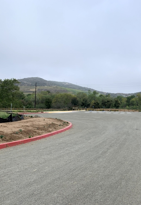 Trailhead parking sign with map on the side of the road entering the refuge parking lot.