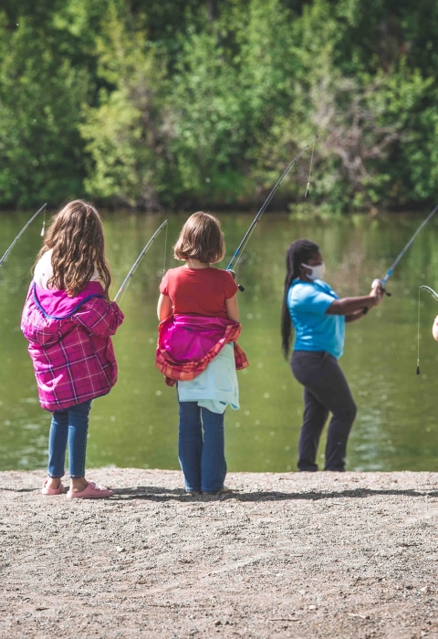 woman in a mask teaching youth how to fish