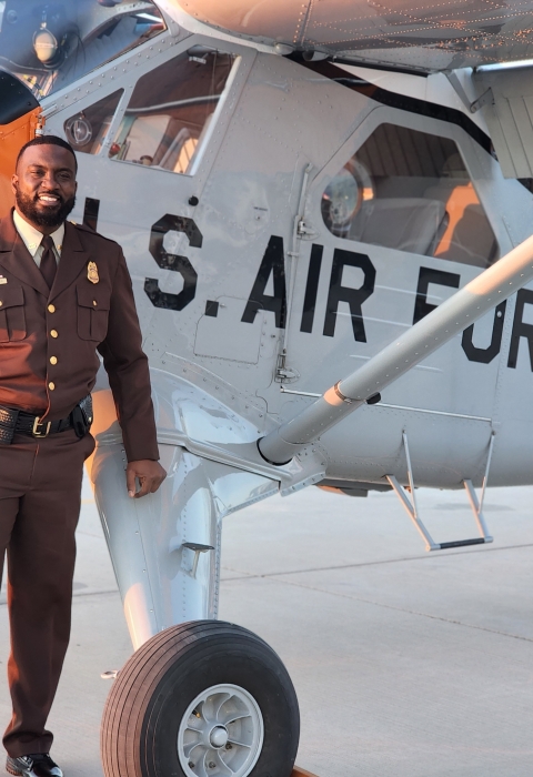 African American man stands in front of plane with "U.S. AIR FORCE" on side