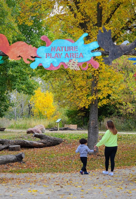 Parent and child walk into nature play area