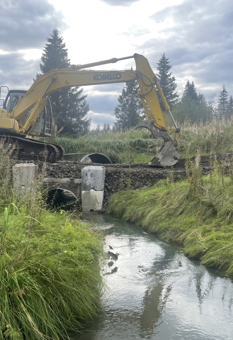 excavator readies ground around a bridge foundation over a river