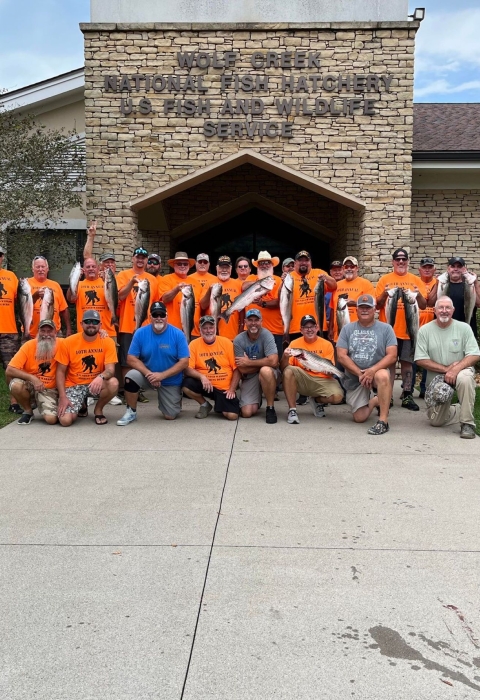 Group of people in orange shirts holding fish