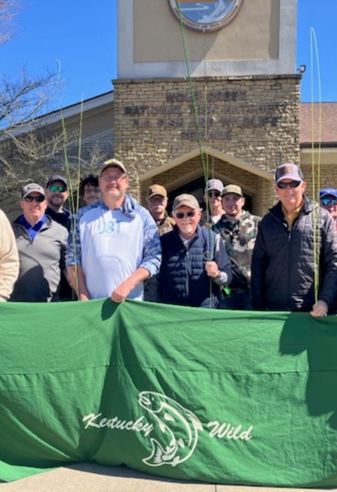 Group of anglers holding rods and a banner for group photo