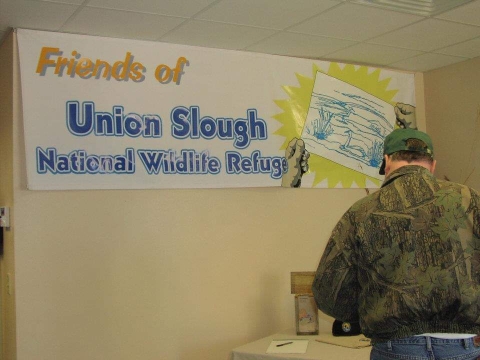 person standing in front of friends of union slough banner