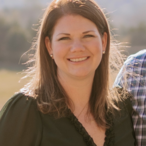 Emily in brown blouse smiling with mountains in background
