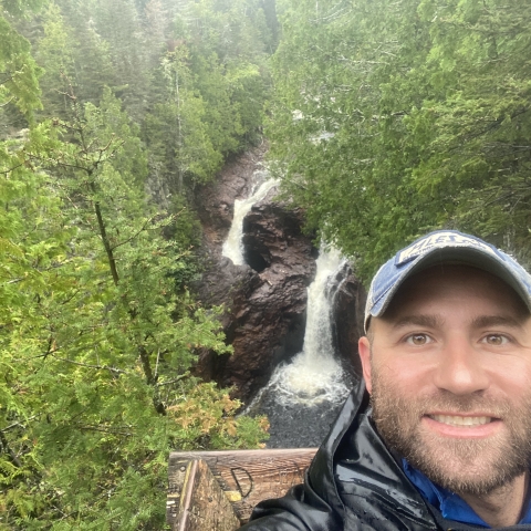 Person standing with a waterfall over their shoulder.