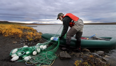man folding a net into a raft