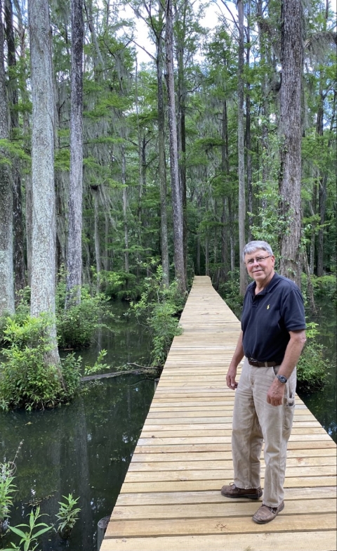 Dr. John Bembry, standing on the bridge crossing his pond.