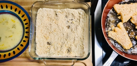 fried pieces of fish next to breading and egg