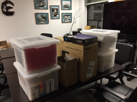 Totes and boxes of files sit with a scanner on a table.