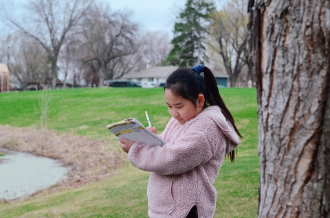 Girl writes in journal while outdoors