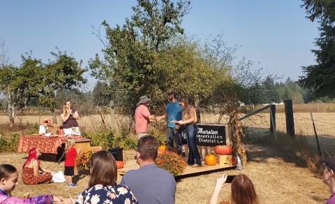 A man receives an award on a platform in an autumnal landscape
