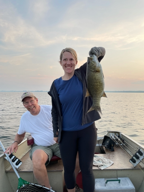 The author's daughter holds a fish while he looks on, in a fishing boat