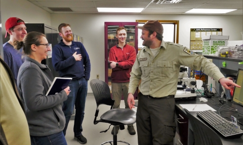 Man in usfws uniform instructs partners on counting rings on carp otolith