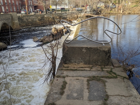 side view of a concrete dam with a stylized fish made of thick metal wire