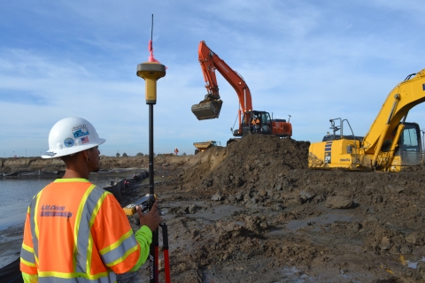Contractor stands on the left viewing bulldozers level restoration site