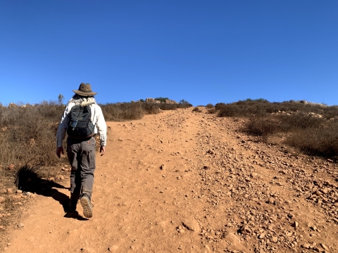 Man on the left of photo hikes up a steep, rocky trail.