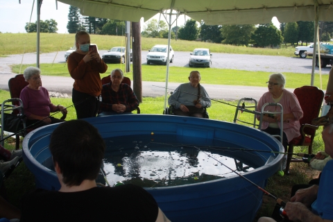 Elderly people sitting around a holding tank with fishing poles