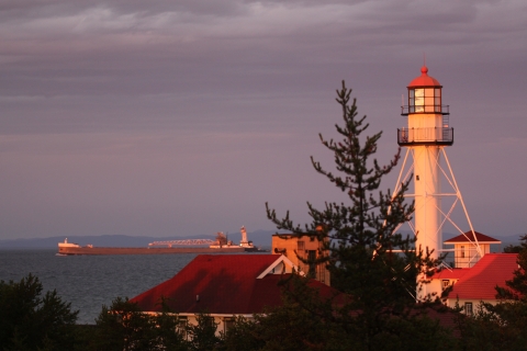 The lighthouse at Whitefish Point in Michigan with a freighter on Lake Superior and Canada in the background. 