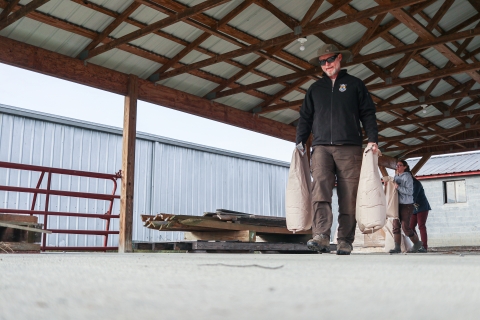 Three people carrying bags of seed