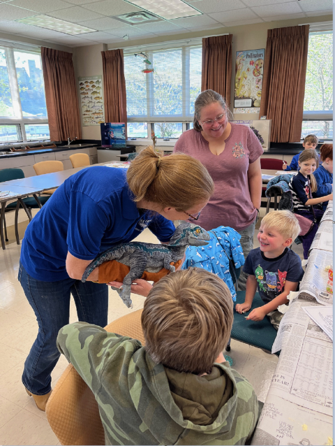 Lady with a dinosaur puppet and a smiling child