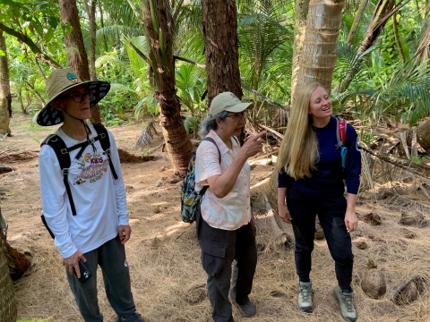 Ruth Utzurrum, center, on Island Dano in Guam. Utzurrum is standing with two other people near palm trees.