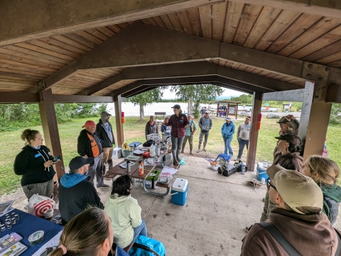 Biologists gather around under a pavilion to hear someone speak.