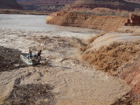 Image of 2 researchers on a raft near a muddy waterfall