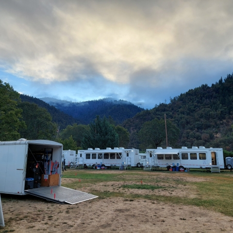 a number of trailers at the base of a smokey mountain